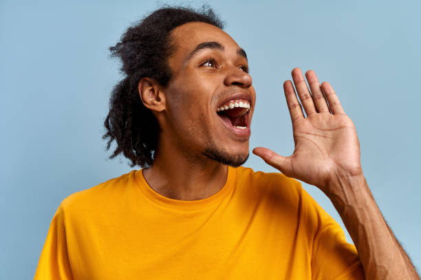 istock Young emotional mixed race guy screams substituting palm on blue background 1380296142