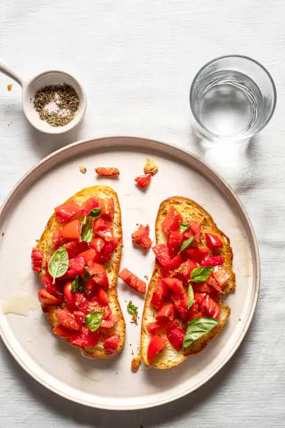 Italian bruschetta with tomatoes, oil and oregano, on a plate. Top view.