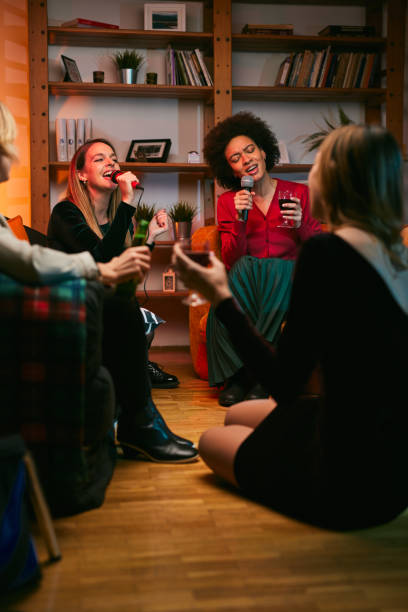 istock Happy multicultural friends sitting at home, laughing, singing, and having fun on karaoke night. 1380330301