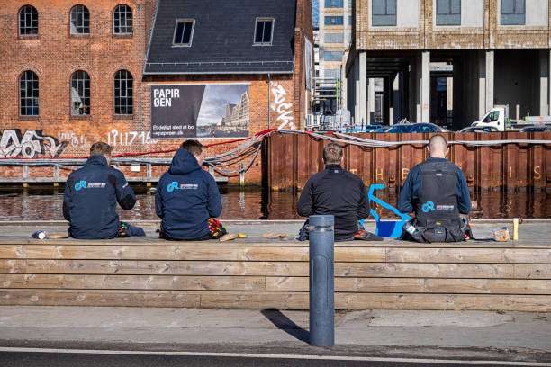 Group of young craftsmen having a lunchbreak outside a construction site in a part of Copenhagen harbor which is under development to a residential area