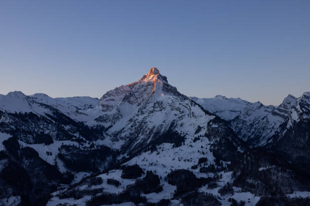 A mountain in the Swiss Alps beautifully set in scene by the morning sun. A majestic sight from a mountain that looks like the Matterhorn. stock photo