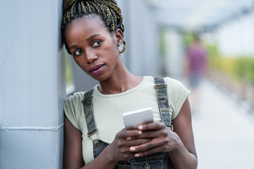 Close up of an young african woman with mobile phone,  standing on a iron bridge