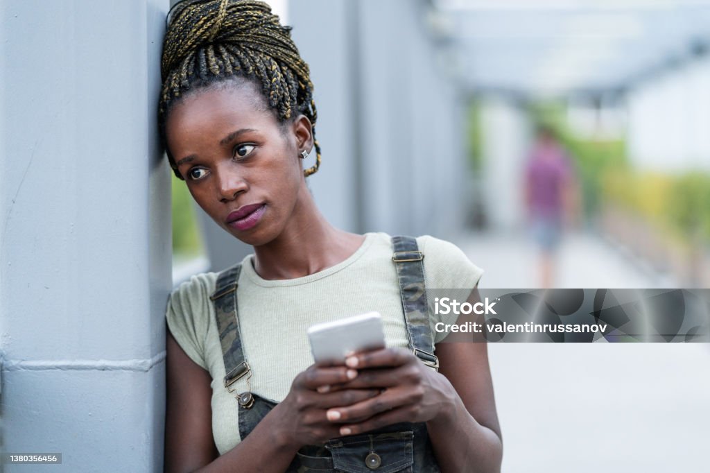 Portrait of an young african woman with mobile phone,  standing on a iron bridge depression Portrait of an young african woman with mobile phone,  standing on a iron bridge Miscarriage Stock Photo