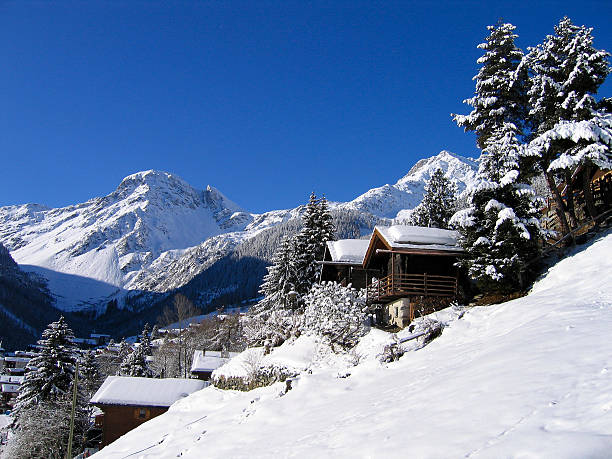 chalets de madera en la nieve blanca valle entre las montañas - foto de stock
