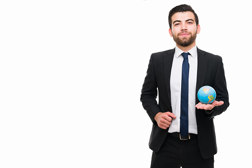Professional young man making international business around the world while holding a globe next to a blank copy space