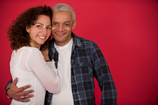 portrait of a mid adult couple hugging on red background