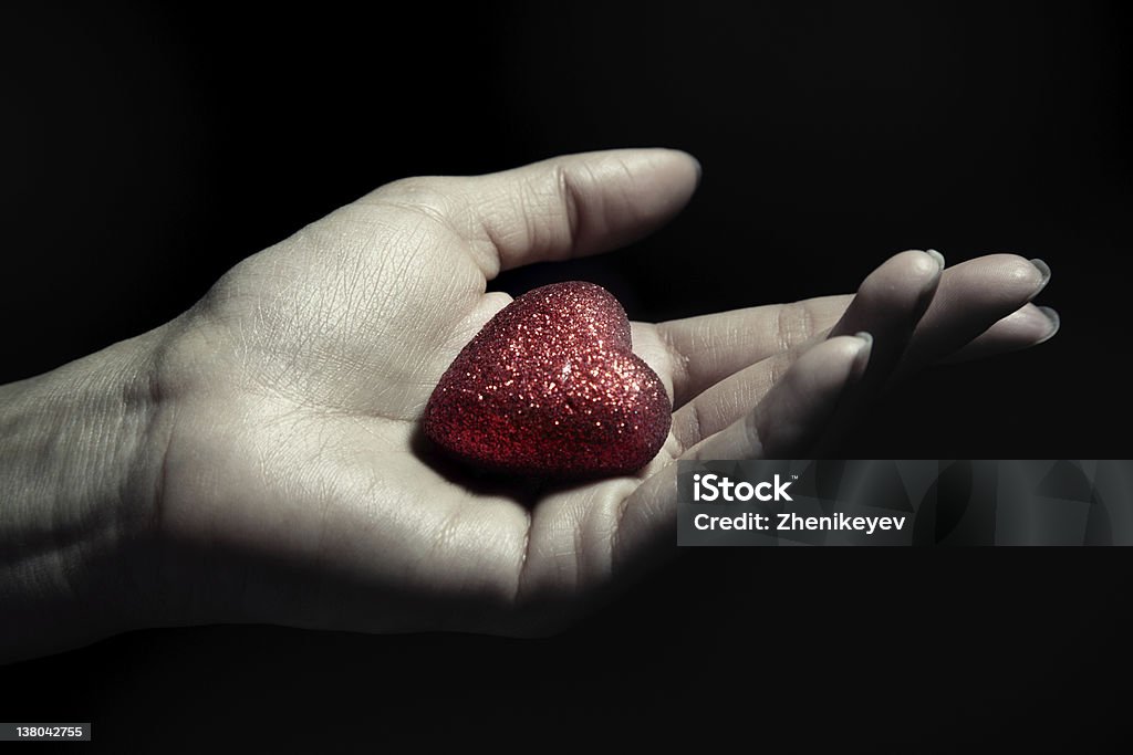 Love Woman hand holding a small heart as a symbol of love Black Background Stock Photo