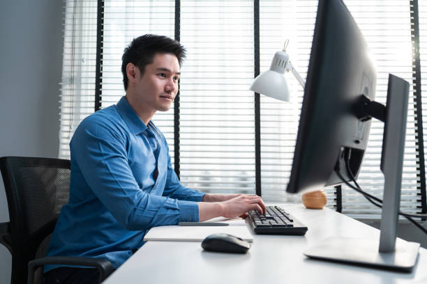 istock Asian handsome business man using laptop computer working in office. Attractive professional male employee worker sitting on table, feel happy and enjoy spending leisure time in corporate workplace. 1380429146