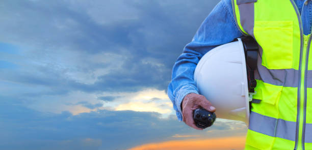 istock Engineer holding hard hat with walkie-talkie on sky background 1380433083