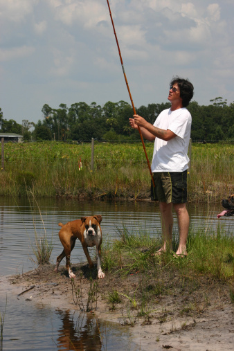 Man fishing with his boxer dog