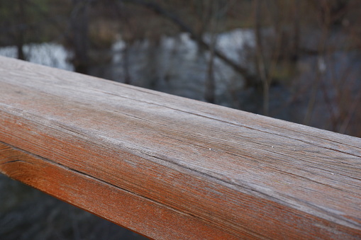 Wood railing of a bridge with river behind