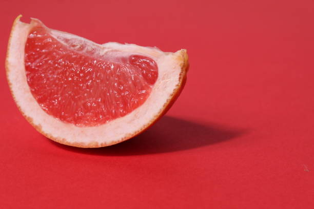 istock a piece of a slice of red grapefruit on a red background with a hard shadow. Fruit creative benefit red on red 1380438710