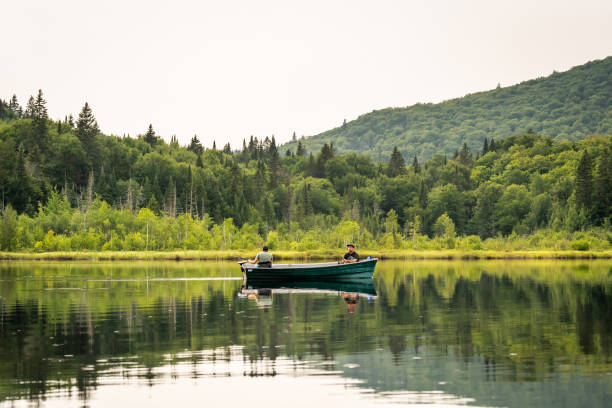 Two men fishing on a lake during a cloudy sunset of summer in Quebec.