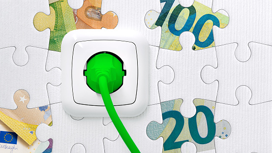 White socket with green power cable in the background a puzzle with euro banknotes