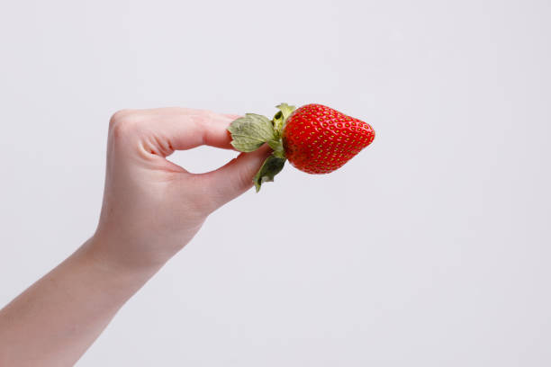 istock Juicy red strawberries in hand on a white background. 1380511430