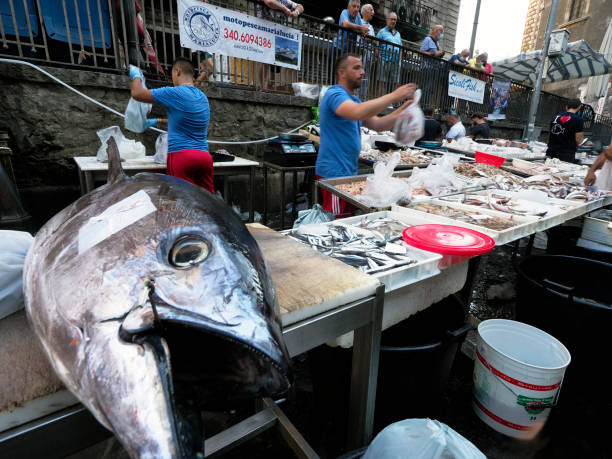 Seafood stall at Old Fish Market (crowded square Alonzo di Benedetto), tourist landmark close to piazza del Duomo, downtown Catania, Sicily, Italy; summer 2021