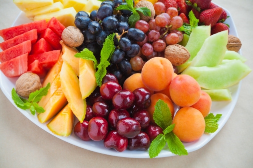 Colorful summer fruit platter with pineapple, watermelon, cherries, apricots, strawberries, cantaloupe, walnuts and mint