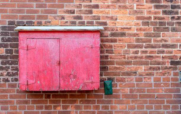 istock Old red wooden window frame on red brick building 1380539666
