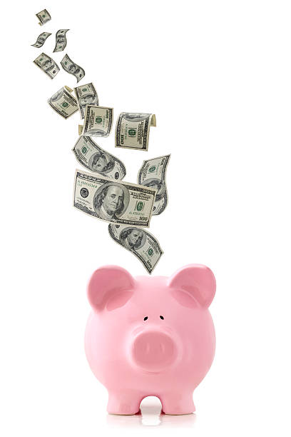 Money Falling into Piggy Bank US currency falling into a pink piggy bank, isolated on white. pennies from heaven stock pictures, royalty-free photos & images