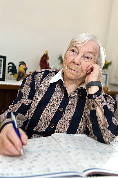 istock Female senior is alone at home and solves a Crossword 138055738