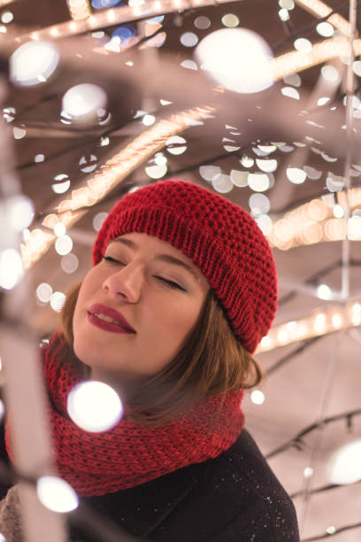 istock Red hat girl standing inside  Christmas tree lights at night 1380569497