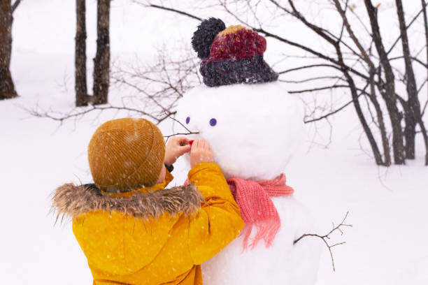 istock Boy  with snowman in park 1380571126