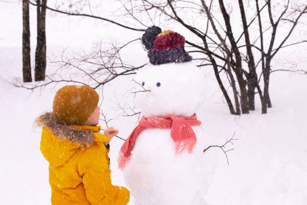 istock Boy and snowman in park 1380571641