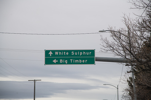 Green overhead directional sign to small towns in central Montana in Northwestern United States of America (USA).