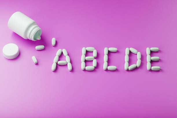 istock Multivitamins A B C D E in capsules from a jar on a pink background. 1380598981