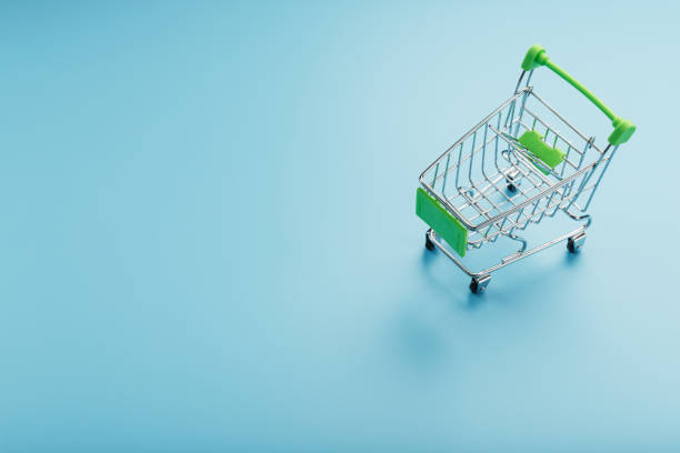 istock Empty miniature supermarket shopping cart on blue background 1380602139