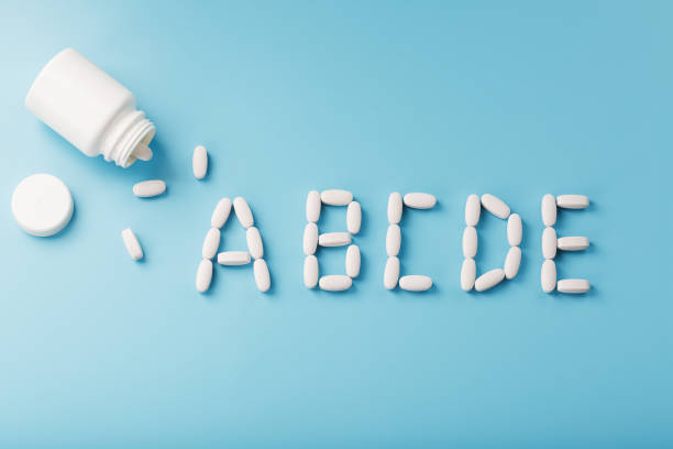 istock Vitamin A B C D E tablets fell out of a white jar on a Blue background. 1380606595