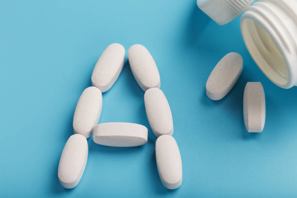 istock Vitamin A pills fell out of a white jar on a blue background. 1380606785