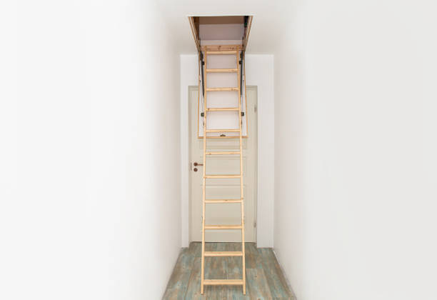 istock Wooden foldable pull up attic stairs ladder at empty white home corridor. Narrow hallway with white walls and blue laminate flooring. 1380610725