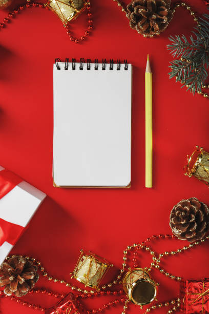 istock Christmas composition with notepad and a pencil for writing wishes with Christmas tree decorations on a red background. 1380612400