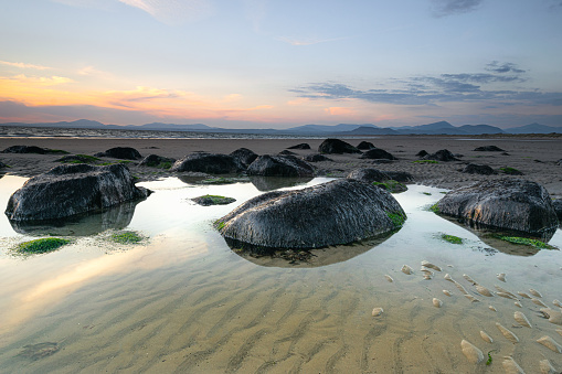 Sunset at Harlech Beach - a seaside resort and community in the North Wales county of Gwynedd. Views across to the Snowdonia Mountains from this scenic rockpool