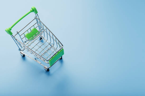 istock Empty miniature supermarket shopping cart on blue background 1380617487
