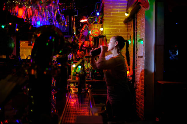 istock Female bartender preparing a cocktail with a shaker while working in a bar or pub. 1380617817