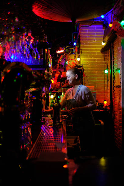 istock Female bartender smiling while working behind the counter of a bar or pub. 1380617821