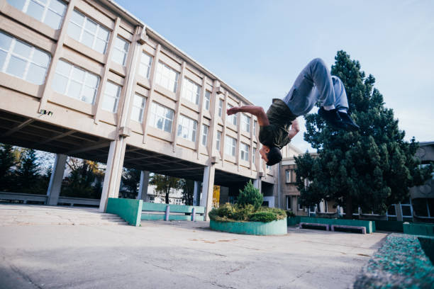 istock Athletic Parkour guy doing backflip and tricks while jumping off and over a concrete wall. 1380617940