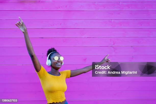 African Girl Dancing Alone With Headphones On Her Ears Listen To Music In A Silent Disc Sense Of Freedom And Joy Contrast Of Yellow And Pink Color Stock Photo - Download Image Now