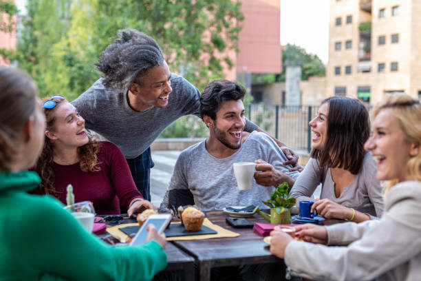 gruppo di amici multietnici che fanno colazione con caffè, cappuccino e muffin al cioccolato, incontro di giovani all'aperto in una caffetteria - muffin blueberry muffin blueberry food foto e immagini stock