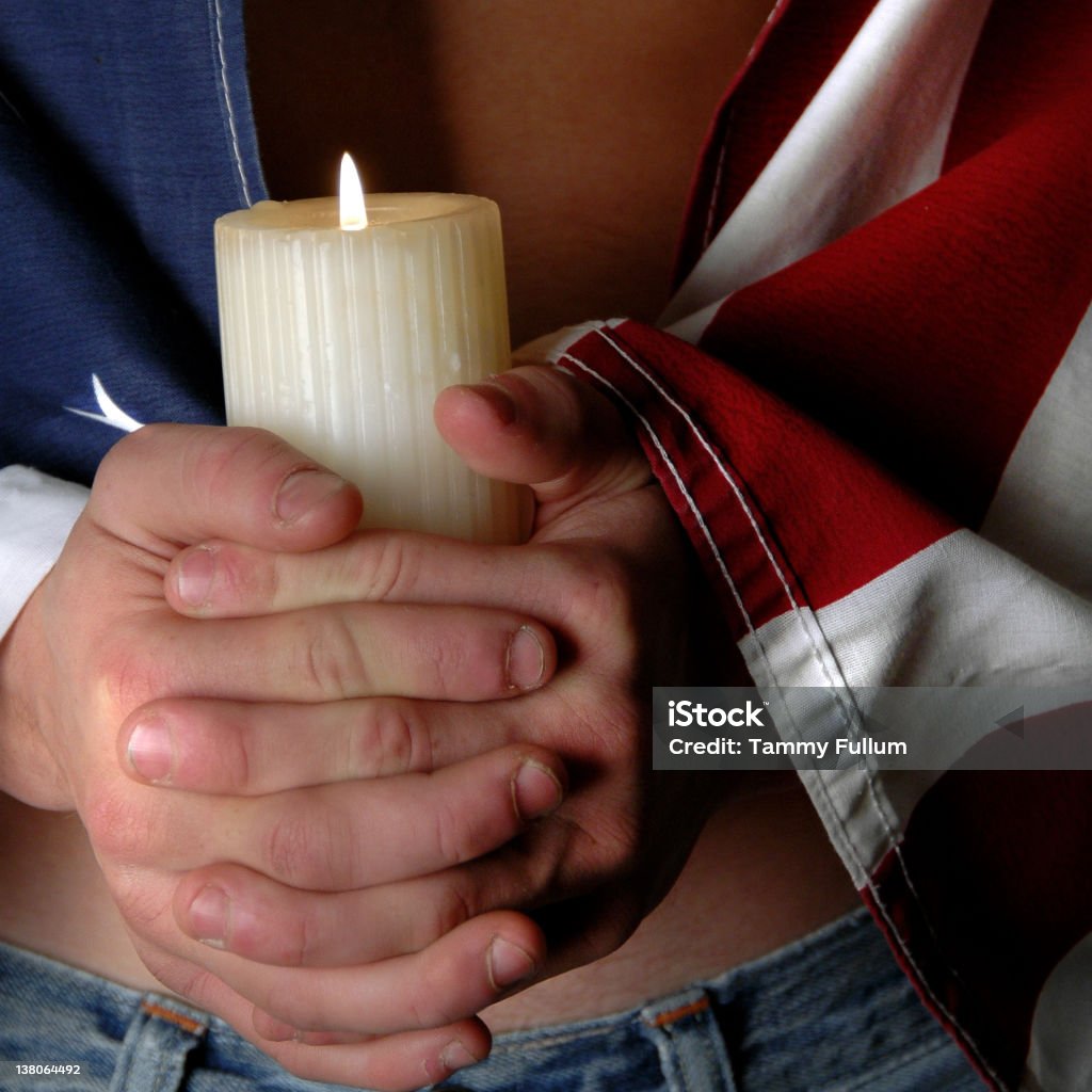 Veteran's American Soldiers Flag close-up of a Young male's body wearing the American flag and holding a candle. American Culture Stock Photo