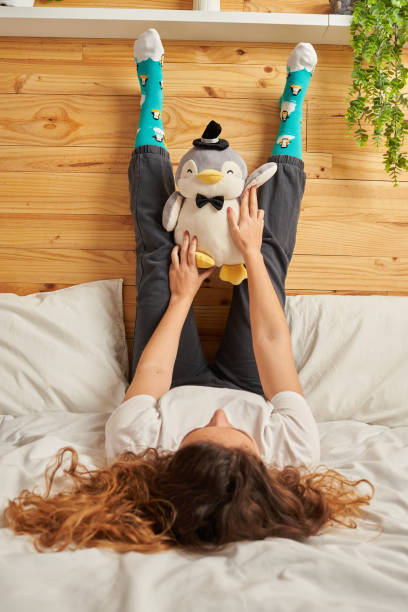 Woman in bed holding stuffed penguin