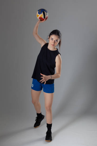 istock Handball player posing on light gray background. Girl jumping with ball. 1380670302