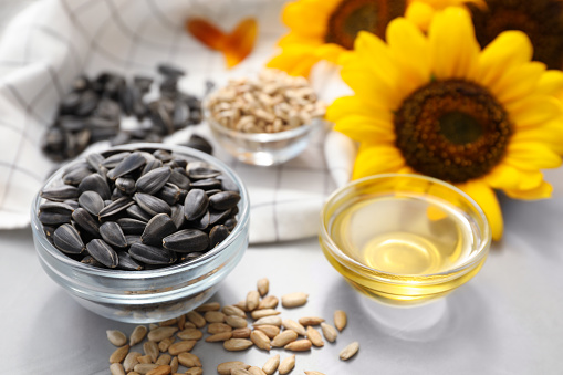 Sunflower oil and seeds on grey table, closeup