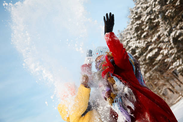 Photo of young family having a snowball fight on a snowy winter day outdoors