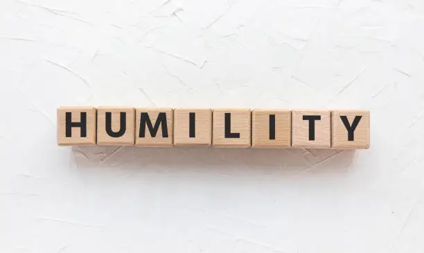 Text HUMILITY on wooden cubes on blue background. Square wood blocks. Top view, flat lay.