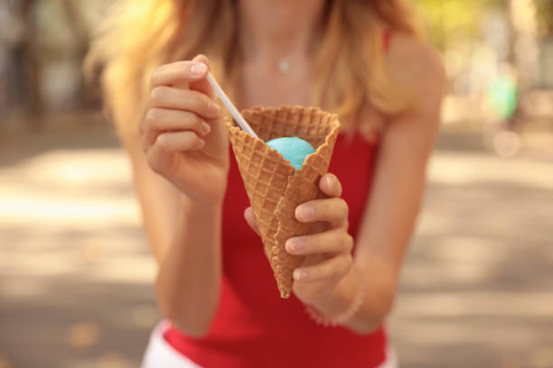 istock Young woman with delicious ice cream in waffle cone outdoors, closeup 1380696477