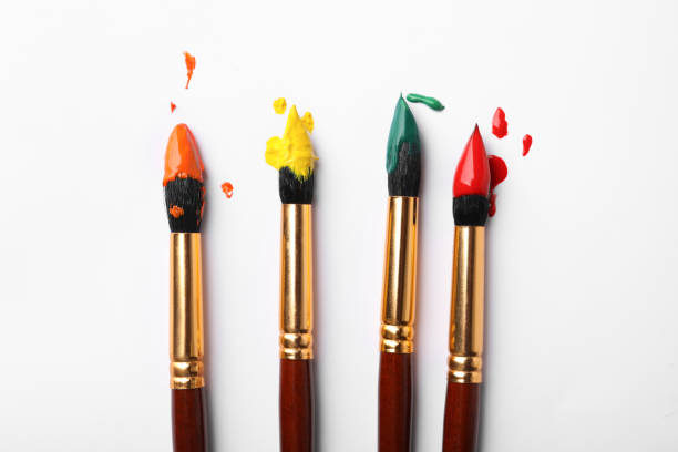 istock Brushes with colorful paints on white background, flat lay 1380698121