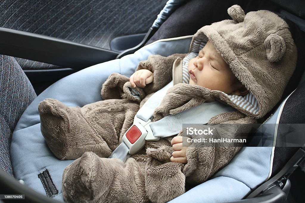 Baby in bear one piece sleeping in a car seat Baby with a bear fancy dress costume sleeping on a baby's seat Baby - Human Age Stock Photo